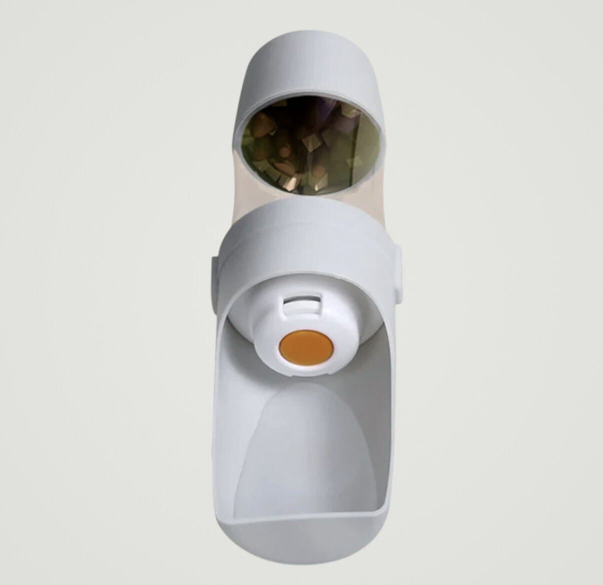 White pet treat dispenser with transparent top holding treats and orange button