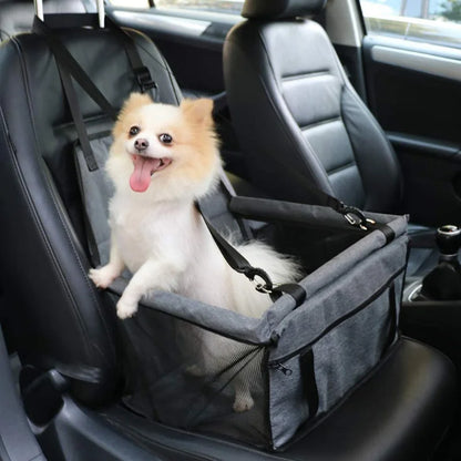 Small happy Pomeranian dog secured in gray pet car seat booster on front passenger black leather car seat